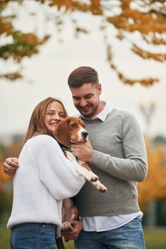 Smiling, having, fun. Lovely ,couple are with their cute dog outdoors photo