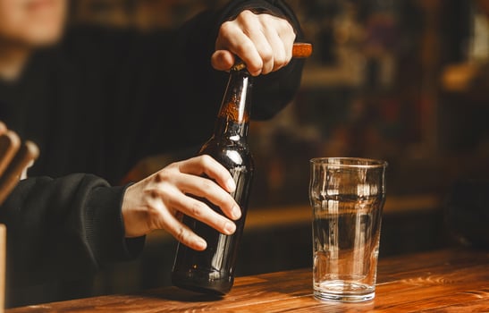 Bartender Opens Bottle of Beer on Polished Bar Counter at Vibrant Tavern During Evening Hours photo