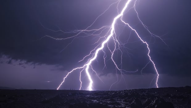Lightning strikes over a dark sky with a large mountain in the background photo