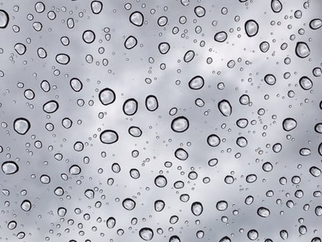 Rain drops at mirror with cloudy sky photo