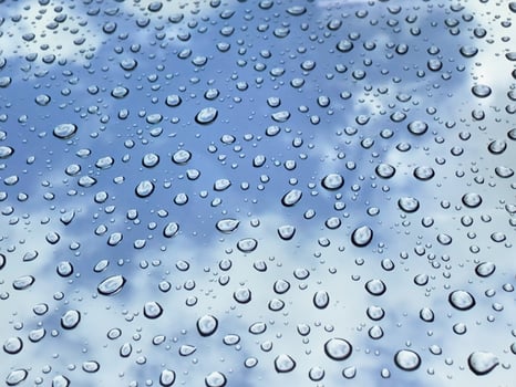 Rain drops at mirror with cloudy blue sky photo