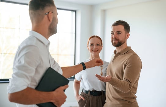 Giving th,,e keys. Realtor shows an apartment to a young couple photo