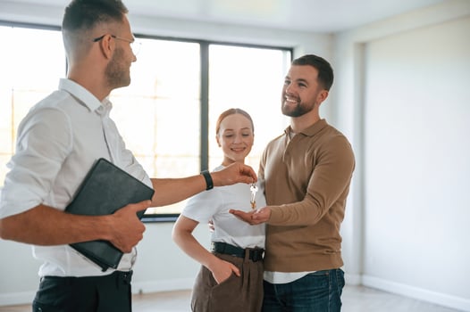 Happy new owners, taking keys. Realtor shows an apartment to a young couple photo