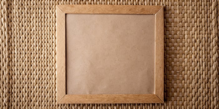 A plain cardboard frame rests on a woven mat. photo