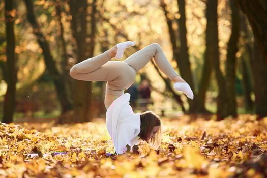 Standing on hands.. Young beautiful woman is doing yoga in the autumn park photo