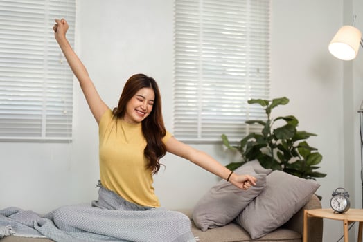 Morning Stretch and Happiness. A young woman happily stretching in bed, welcoming the day with an infectious smile and positive energy. photo
