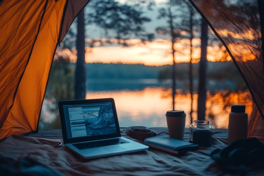 Laptop and coffee inside camping tent during golden hour overlooking lake photo