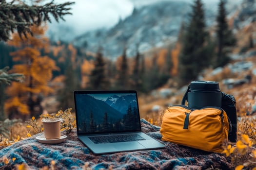 Laptop, coffee and backpack on blanket in mountains with colorful autumn trees photo