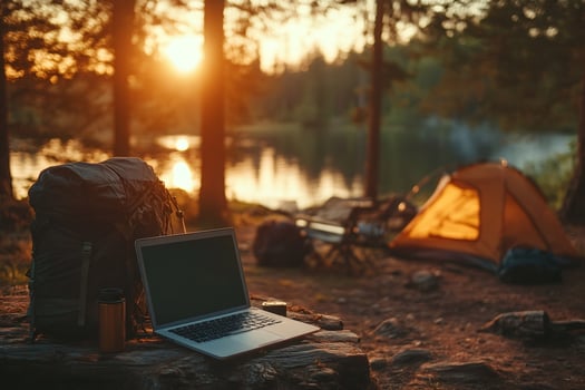 Laptop, backpack and tent by the lake at sunset in the woods, working remotely while camping photo