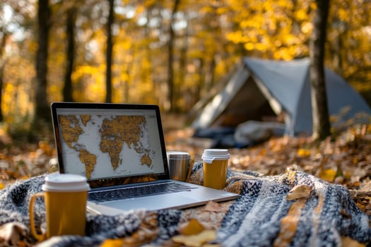 Laptop showing world map with tent in autumn forest, planning next travel destination photo