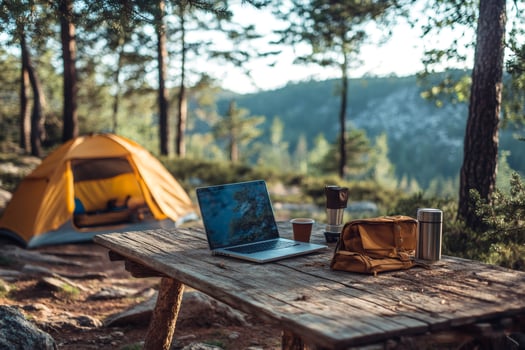 Freelancer working remotely from camping table with laptop in forest photo
