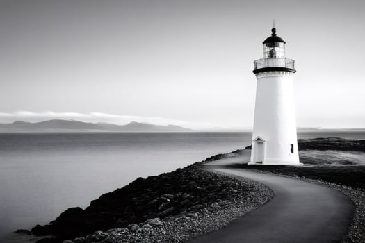 Lighthouse guiding ships on rocky coast in black and white photo