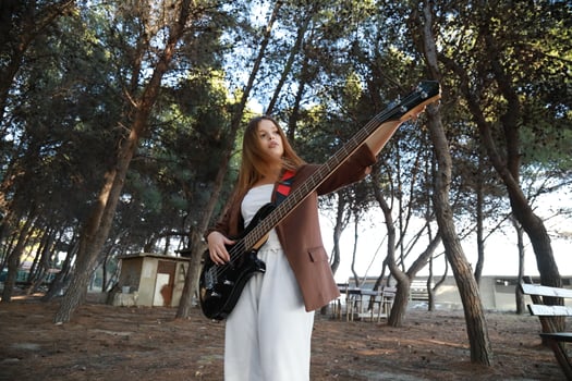Girl Adjust Handles Outdoor To Tune Bass Musical Instrument In The Park photo