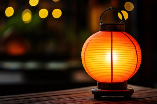 Round orange paper lantern lighting up a wooden table at night photo