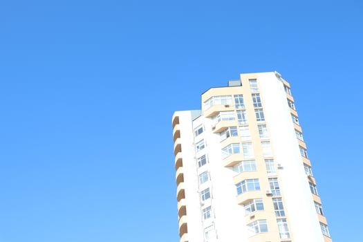 A contemporary modern highrise building prominently set against a clear, bright blue sky photo