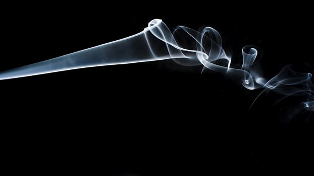 Smoke billowing out of a horn on a black background photo