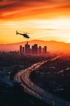 Helicopter flying over los angeles skyline at sunset with busy highway traffic photo