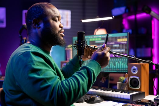 Artist songwriter performing his new musical creation in home studio, recording a new song for the acoustic version launch. Young composer uses phone to read melodic elements and verses. photo