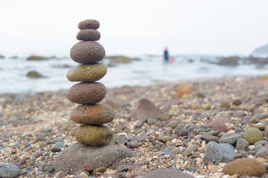 A carefully balanced stack of smooth pebbles on a rocky beach, symbolizing harmony, mindfulness, and stability. photo