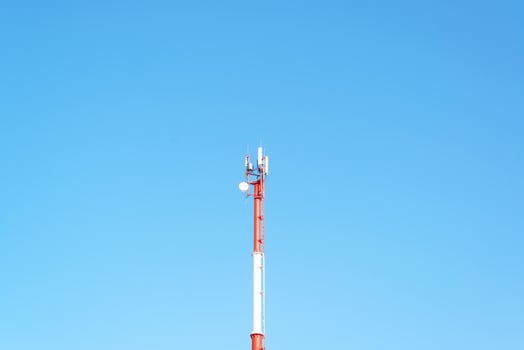 Mobile tower of cellular, radio and internet communications against the background of a clear blue sky photo