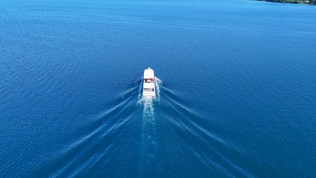 Cruising gracefully across the sparkling blue waters of a serene lake on a sunny day with a boat leaving tranquil ripples behind photo