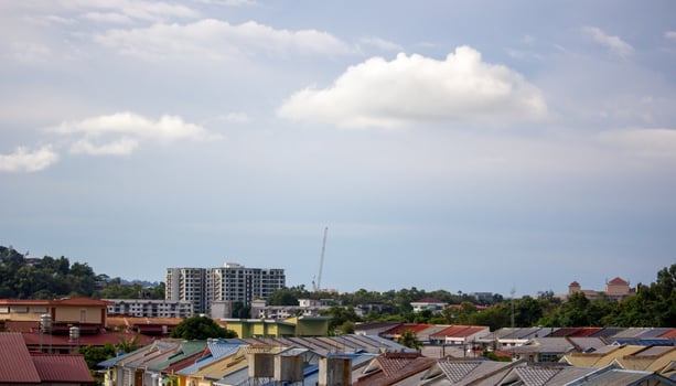 Urban residential rooftops beneath a clear blue sky with soft white clouds in peaceful daytime setting photo