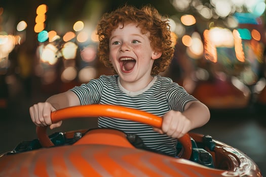 Redhead child enjoying bumper cars at amusement park photo