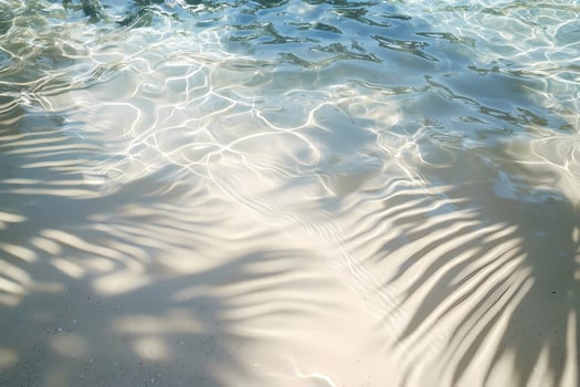 Crystal clear water rippling with palm tree shadows on sandy beach photo