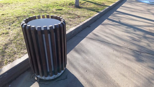 Empty wooden trash bin near park path in sunlight photo