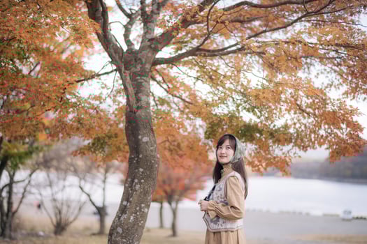 A woman standing under a tree in front of a lake photo