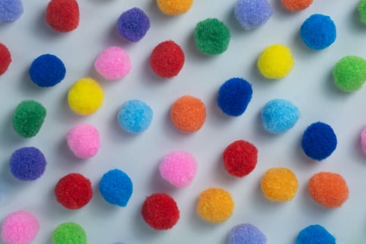 Multicolor Craft Pom Poms Spread on Soft White Surface photo