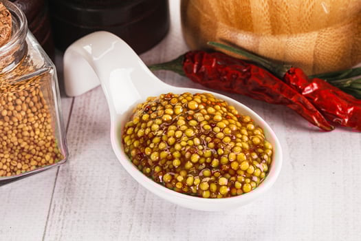 A white spoon with mustard seeds and chili peppers photo