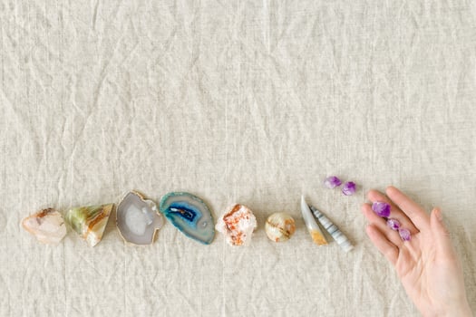 Row of healing crystals, female hands holding small amethyst gemstones rocks for magic crystal ritual, chakra relaxation, reiki healing therapy, aura readings. Top view magic minerals photo