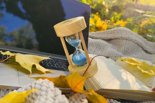 hourglass and laptop in autumn leaf. Cozy autumn or winter concept. photo