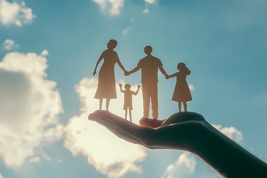 Hand holding paper cutout family under cloudy sky photo