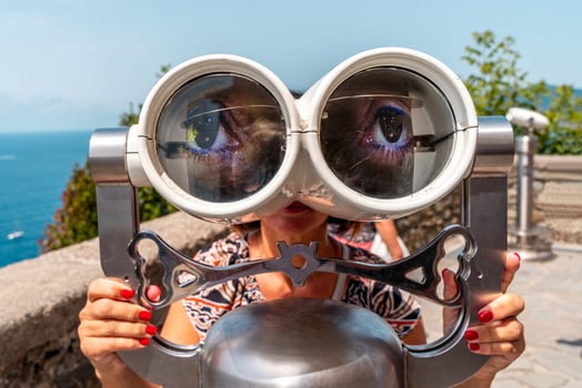a woman is looking through tourist binoculars on a terrace by the sea photo