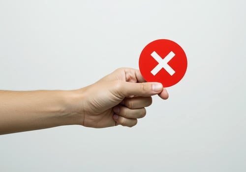A person holding a red x sign on a white background photo