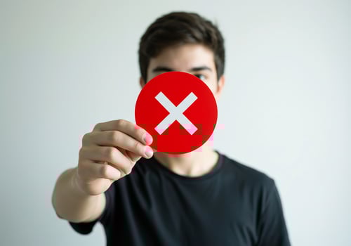 A man holding up a red cross with an x on it photo