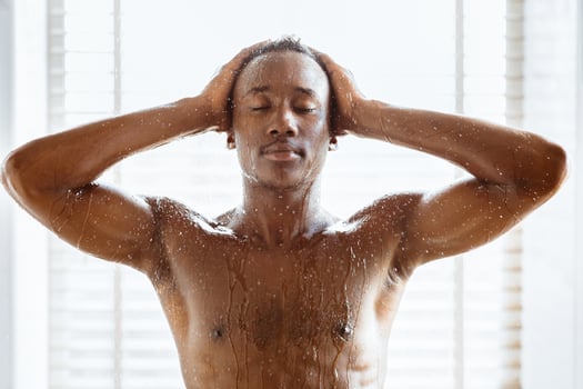 Morning Shower. Muscular Black Guy Washing Body And Head Standing With Eyes Closed Enjoying Hot Water In Modern Bathroom Indoor. Wellness And Relaxation, Hygiene, Male Bodycare Concept photo