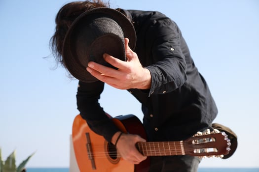 Street Artist Takes a Bow After Playing Classical Guitar on the Beach Outdoor Near Ocean photo
