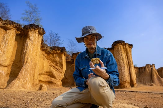 Asian geologist is exploring and surveying the sample rock on the natural sandstone canyon quarry site for scientific research and archeology for understanding earth photo