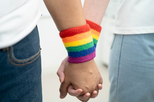 LGBT couple woman holding hand wearing rainbow wristband. photo