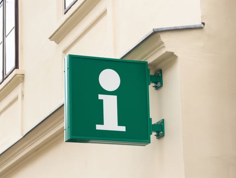 Green information sign with white 'i' on building wall photo