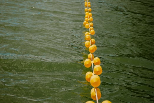 Yellow buoys floating on lake water surface for nautical safety and boundary marking. Weekend concept near the forest and lake photo