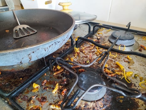Dirty stovetop and pan after cooking. Shows realistic kitchen mess, chaos, food waste. Useful for concepts like housework, laziness, or busy lifestyles. photo