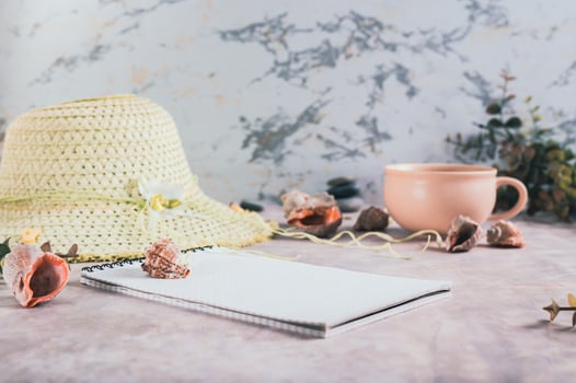 Travel planning notebook, hat, seashells and cup of coffee on table photo
