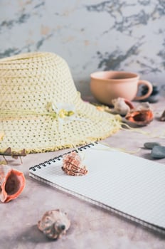Travel planning notebook, hat, seashells and cup of coffee on table vertical view photo