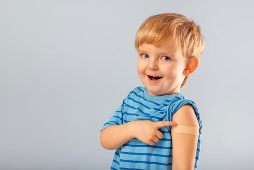 Vaccinated kid boy showing arm with adhesive bandage after vaccine injection photo
