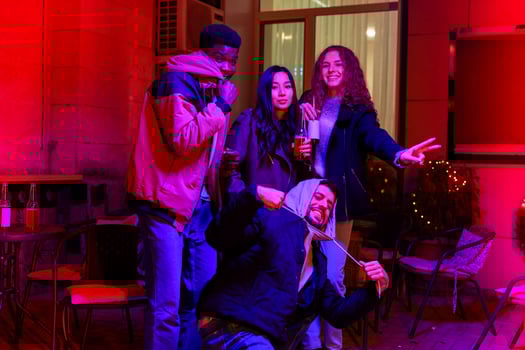 Friends enjoying a lively evening gathering outdoors in a vibrant setting with colorful lights during autumn photo