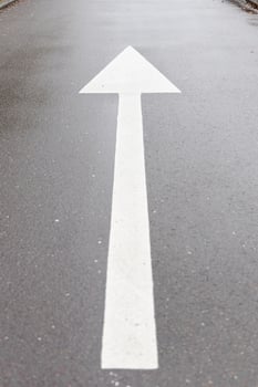 White arrow symbol in a straight direction on an asphalted avenue, transport concept photo